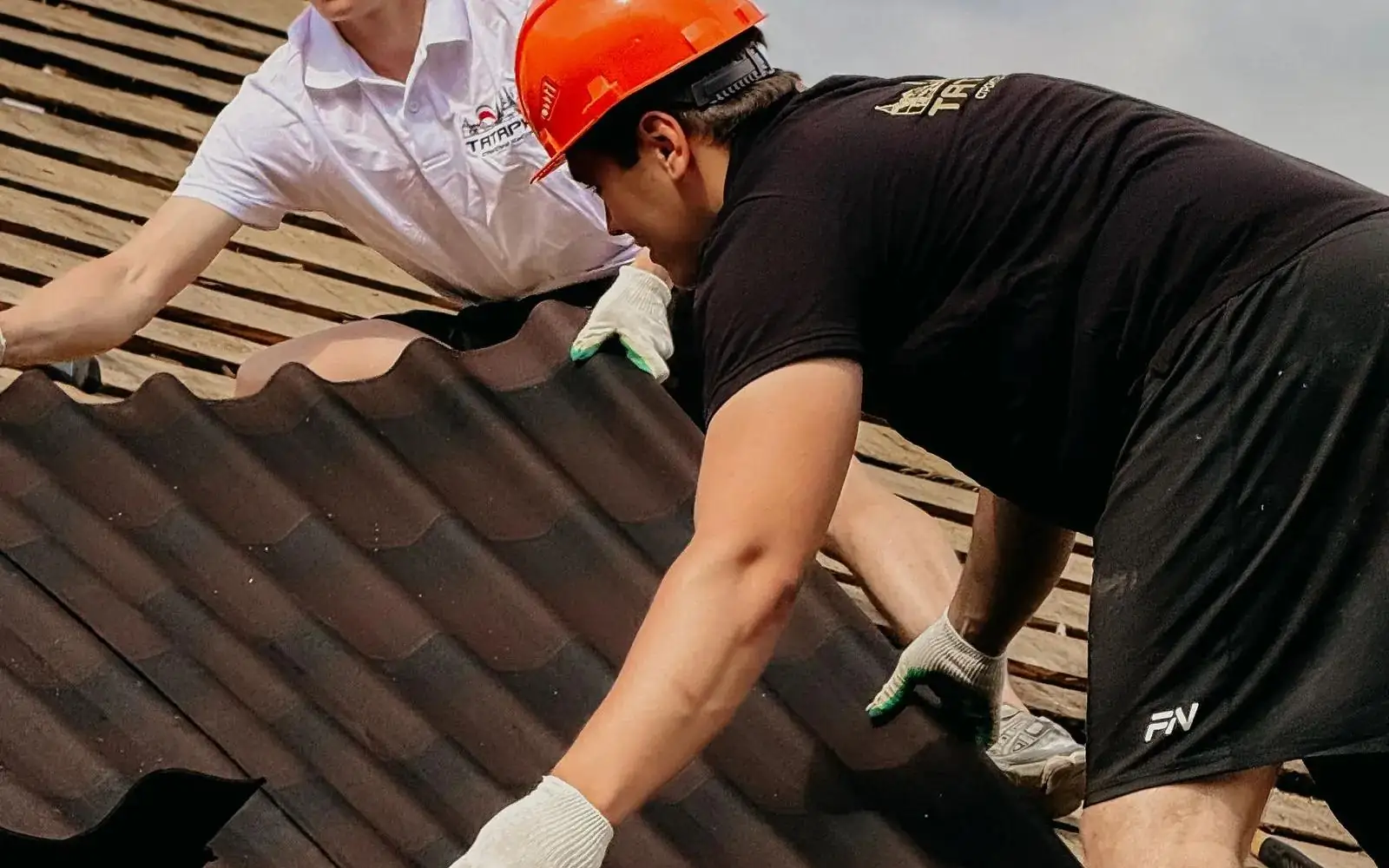 A crew fitting new tiles to a residential roof